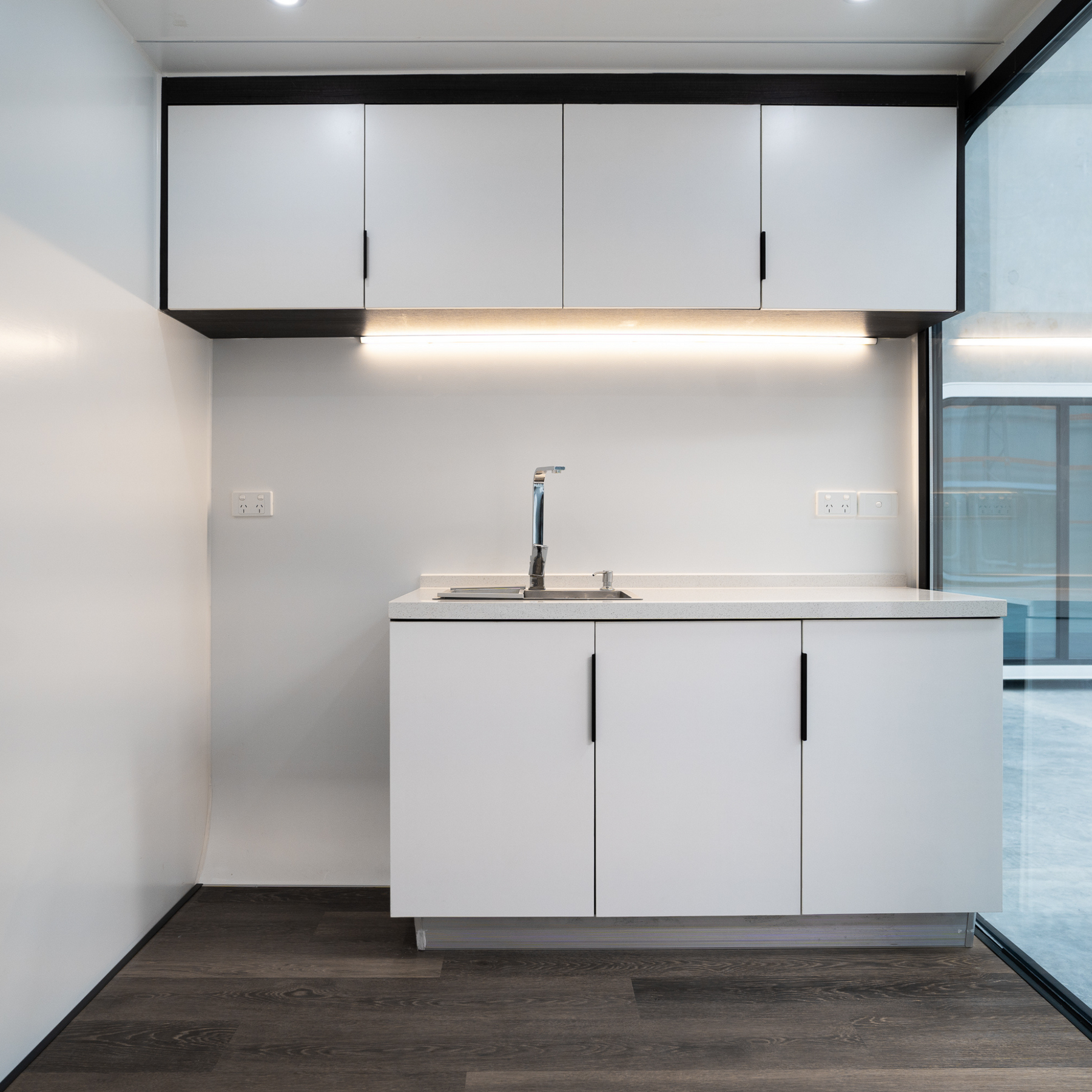 built-in kitchenette in spacee pods with soft-close cabinetry, sink and LED strip lighting