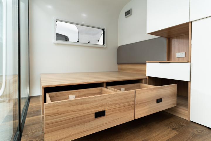 WhiteHouse Spacee design interior with laminate plank flooring and fully installed bedframe and under-bed storage compartments with black drawer handle